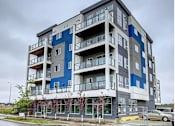 Thumbnail 1 of 11 - A large apartment building with balconies and multiple windows.
