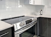 Thumbnail 10 of 11 - A modern kitchen with a stove top oven and a sink.