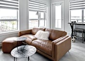 Thumbnail 2 of 11 - A brown leather couch with a round table in front of it.