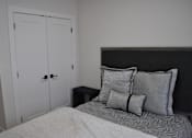 Thumbnail 4 of 9 - A bed with a white comforter and two pillows sits in a room with a white closet at The Laurent at Laurel Apartments, Edmonton, Alberta