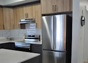 Thumbnail 6 of 9 - A modern kitchen with a stainless steel refrigerator and wooden cabinets at The Laurent at Laurel Apartments, Alberta