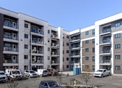 Thumbnail 5 of 31 - A parking lot with cars and apartment buildings in the background.at The Pointe at Riverview, Edmonton, AB T6M 3H4