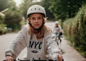 Thumbnail 14 of 15 - a young girl riding a bike down a street
