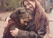 Thumbnail 10 of 15 - a girl hugging another girl while looking at a cell phone