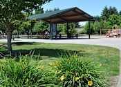 Thumbnail 3 of 11 - A black post is in the foreground of a park with a playground in the background.