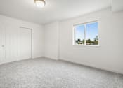 Thumbnail 8 of 13 - A room with a white door and a window showing a view of trees and a house.
