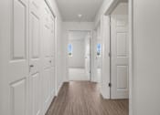 Thumbnail 11 of 13 - A long hallway with white doors and wood floors.