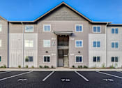 Thumbnail 4 of 13 - A large building with a parking lot in front of it.