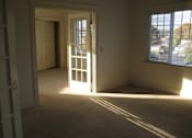 Thumbnail 20 of 21 - A room with a carpeted floor, a door, and a window.