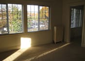 Thumbnail 19 of 21 - A room with a carpeted floor, a window with a view of a parking lot, and a radiator.