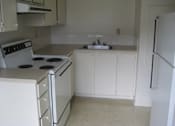 Thumbnail 4 of 21 - A kitchen with white appliances and cabinets.