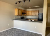 Thumbnail 6 of 9 - A kitchen with a black refrigerator and wooden cabinets.