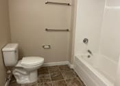 Thumbnail 8 of 9 - A white toilet sits next to a bathtub in a bathroom.