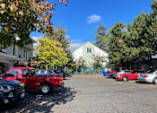 Thumbnail 3 of 5 - A red pickup truck is parked in a lot with other vehicles.