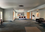 Thumbnail 4 of 5 - A grey hallway with a table and chairs in the middle.