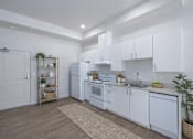 Thumbnail 2 of 38 - A kitchen with white cabinets and appliances, a wooden floor, and a rug on the floor.