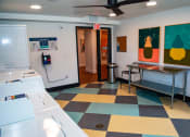 Thumbnail 11 of 25 - a laundry room with a checkered floor and a refrigerator and a table
