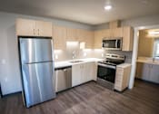 Thumbnail 7 of 16 - A modern kitchen with stainless steel appliances and wooden cabinets.