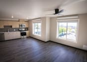 Thumbnail 10 of 16 - A spacious kitchen and living room with hardwood floors and large windows.