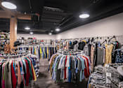 Thumbnail 13 of 16 - A clothing store with a variety of clothes on display.
