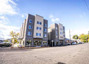 Thumbnail 3 of 16 - A street view of a row of modern apartment buildings.