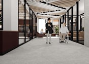 Thumbnail 21 of 30 - A woman in a wheelchair is being assisted by two other women in a modern hallway.