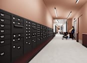 Thumbnail 30 of 30 - A hallway with a series of black lockers on the left and a woman pushing a stroller on the right.