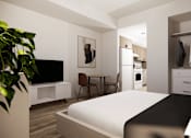Thumbnail 10 of 30 - A modern bedroom with a large bed, a TV, a chair, a dining table, and a plant.