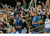 Thumbnail 5 of 10 - A crowd of people at a sporting event with their hands raised.