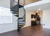 Thumbnail 10 of 10 - a spiral staircase leads up to a loft in a home with a kitchen in the background