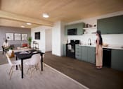 Thumbnail 17 of 41 - A woman is standing in a kitchen with a table and chairs.