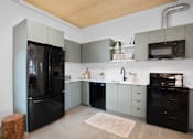 Thumbnail 36 of 41 - A kitchen with black appliances and grey cabinets.