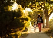 Thumbnail 3 of 4 - a mother and child walking down a sidewalk