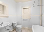 Thumbnail 12 of 35 - A white toilet sits next to a sink in a bathroom.