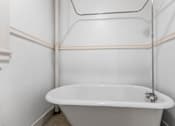 Thumbnail 13 of 35 - A white bathtub with a shower head attached to the wall.