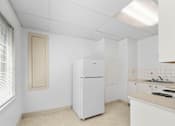 Thumbnail 21 of 35 - A white kitchen with a fridge and a window.