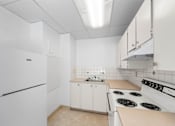 Thumbnail 22 of 35 - A white kitchen with a refrigerator, stove, and cabinets.