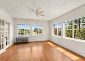 Thumbnail 15 of 35 - A room with a ceiling fan and large windows.