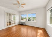 Thumbnail 20 of 35 - A room with a ceiling fan and a window with a view of trees.