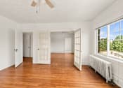 Thumbnail 16 of 35 - A room with wooden floors and white walls.