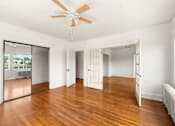 Thumbnail 17 of 35 - A room with a ceiling fan and wooden floors.