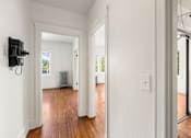 Thumbnail 18 of 35 - A hallway with a black electrical box on the wall.