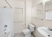 Thumbnail 33 of 35 - A white bathroom with a toilet, sink, and bathtub.