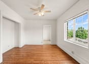 Thumbnail 28 of 35 - A room with a ceiling fan and a window overlooking a street.