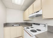 Thumbnail 31 of 35 - A kitchen with a white stove and beige cabinets.