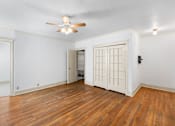 Thumbnail 5 of 35 - A room with a ceiling fan and wooden floors.