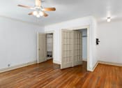 Thumbnail 8 of 35 - A room with a ceiling fan and wooden floors.