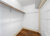 Thumbnail 10 of 35 - A white wall with a brown wooden floor and a white door.