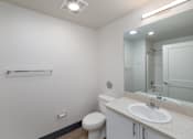 Thumbnail 25 of 38 - A white bathroom with a toilet, sink, and mirror.