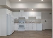 Thumbnail 21 of 38 - A white kitchen with a refrigerator, oven, and sink.